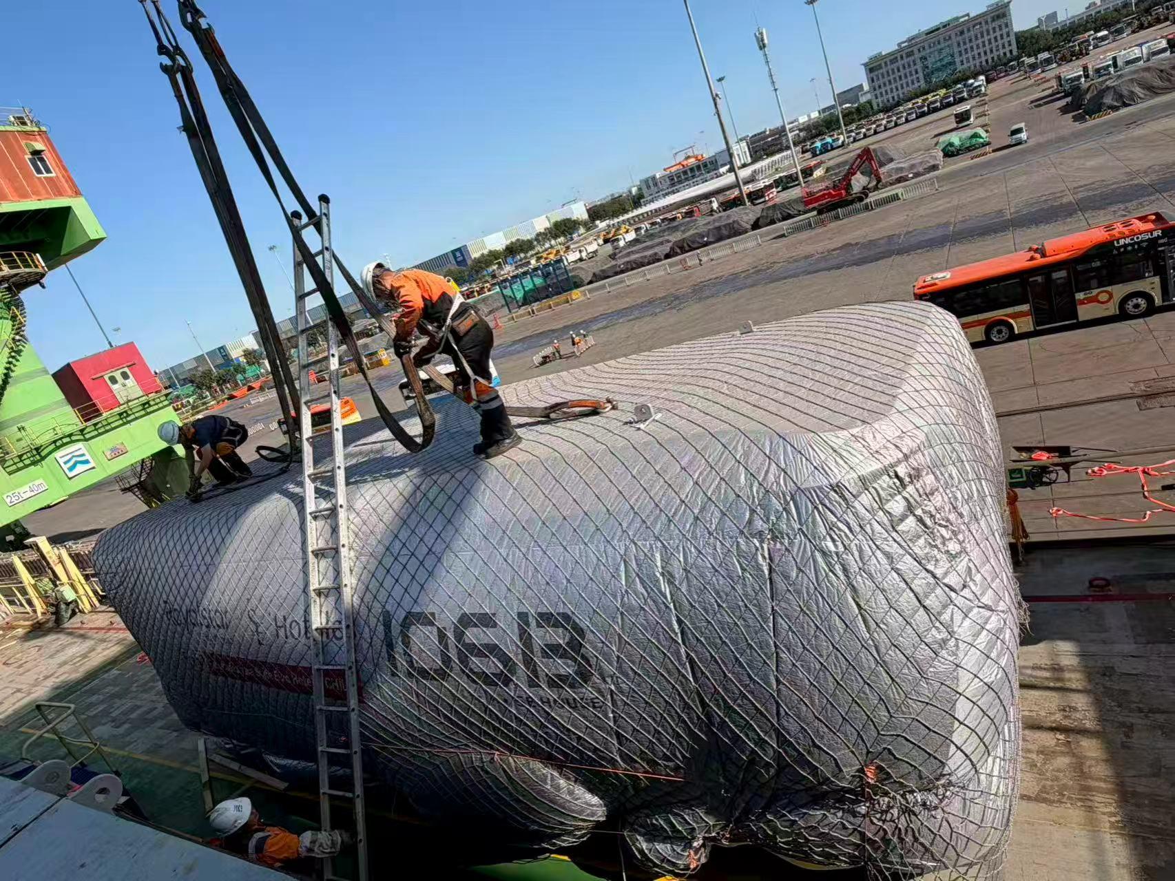 Capsule House envuelta y asegurada con eslingas durante la maniobra de embarque